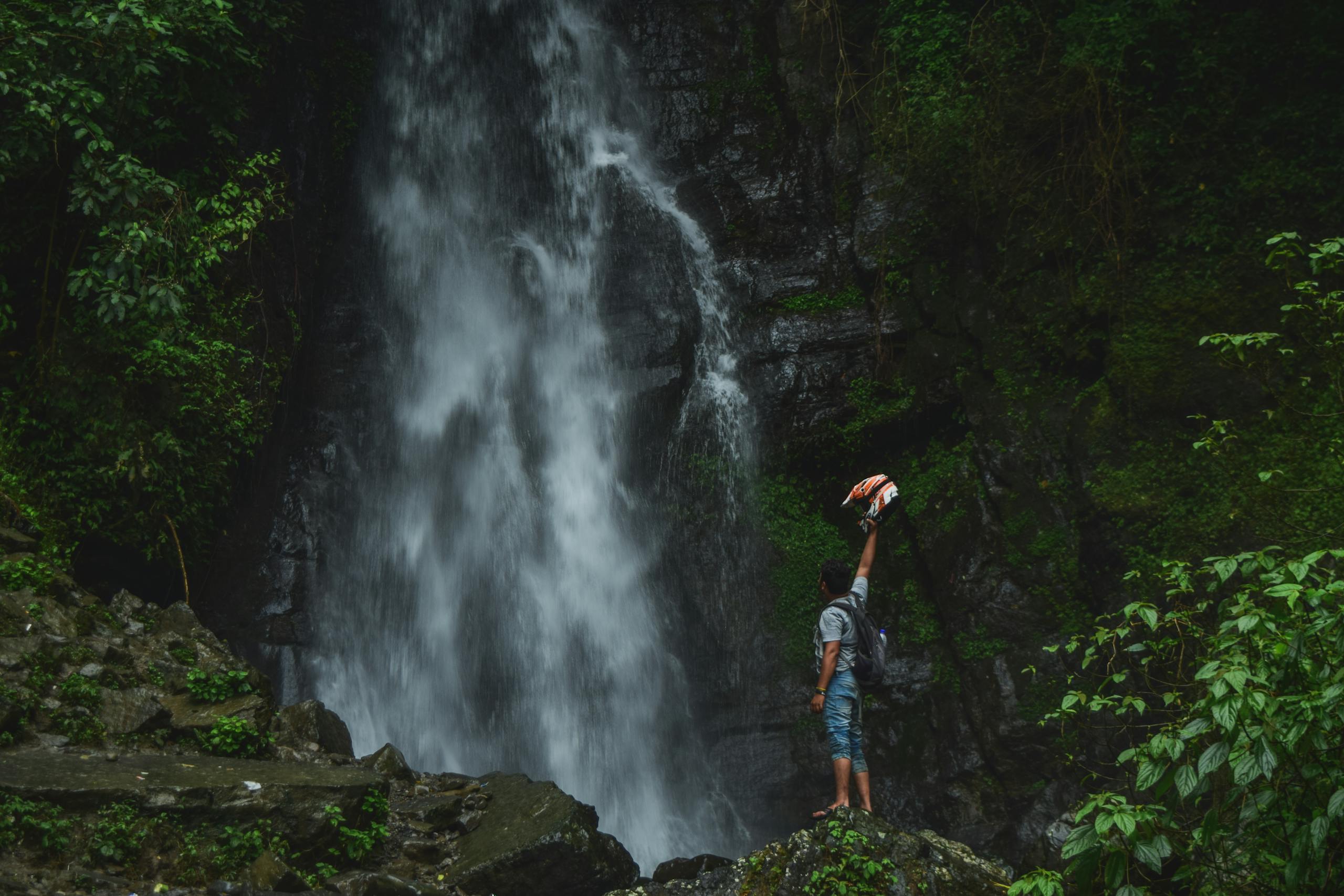 A man celebrating nature at a stunning jungle waterfall, embracing the adventure.